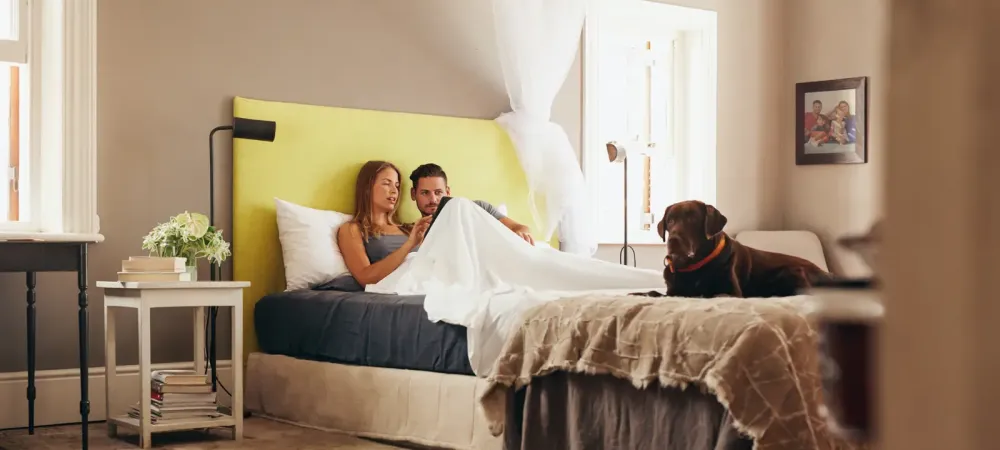 couple talking with dog in bed