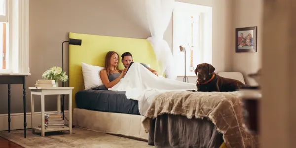 couple talking with dog in bed